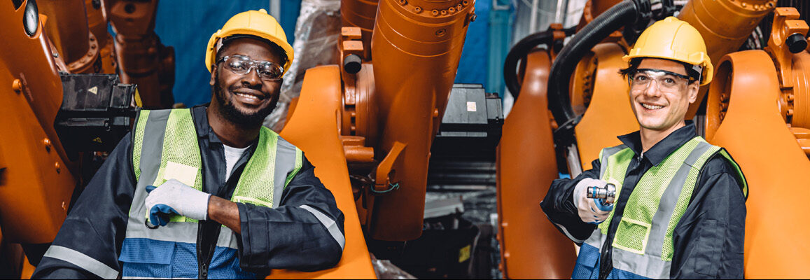 Two employees in an industrial setting wearing personal protective equipment.