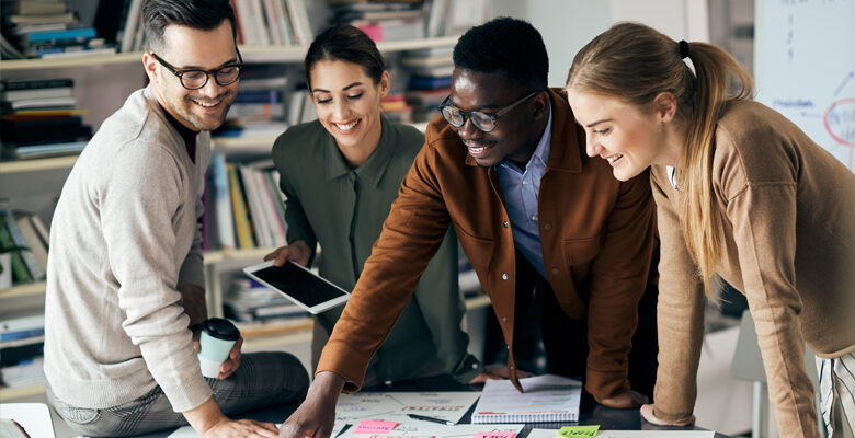 Four employees in an office setting working together.