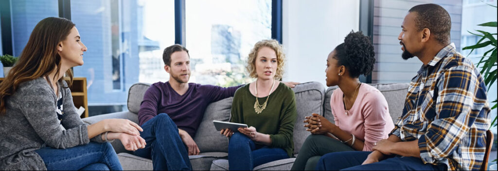 A group of people sitting on the couch having a discussion.